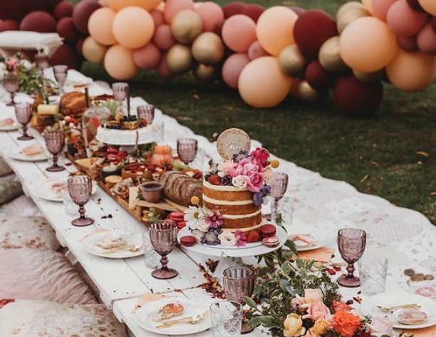 Colorful outdoor party table laid out with food and a balloon display