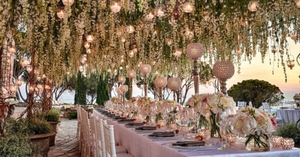 Outdoor wedding reception with florals and lights hanging from ceiling