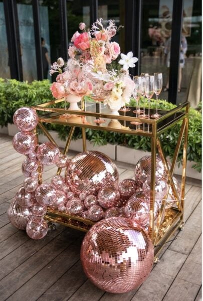 Pink disco balls used as decor on a bar cart